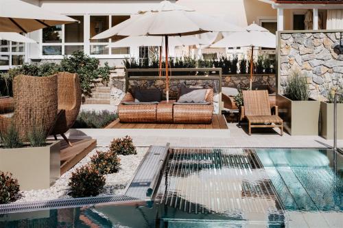 a pool with a couch and chairs next to a house at Bergergut Geniesserhotel in Afiesl
