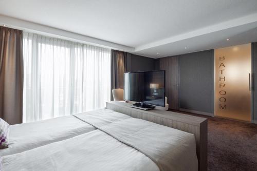 a bedroom with a large bed and a flat screen tv at Van der Valk Hotel Haarlem in Haarlem
