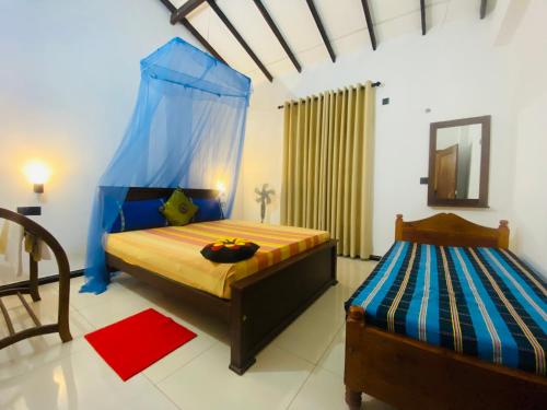 a bedroom with two beds and a blue canopy at Priyavimana resort in Habarana