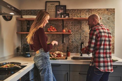 a man and a woman standing in a kitchen at SCHLOSS Zermatt - CBD & Adaptogenic Spa and Sport Hotel in Zermatt