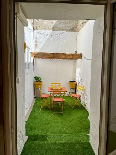 une terrasse avec une table et des chaises sur de l'herbe verte dans l'établissement Maison de Village - Standing - Centre Historique, à Sigean