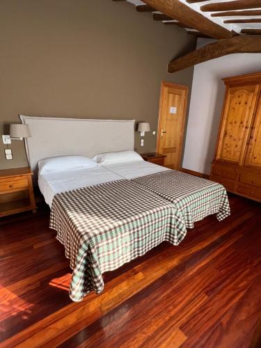 a bedroom with a bed with a checkered blanket at Hotel - Restaurante La Posada de Santa Rita in Enciso