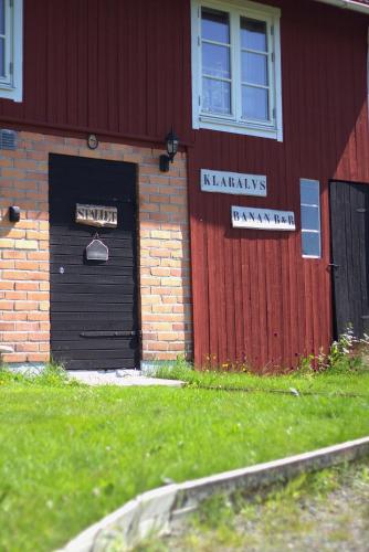 a red building with a black door and signs on it at B&B Klarälvsbanan in Deje