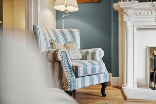 a blue and white striped chair in a living room with a fireplace at 2-Bedroom Stunning, Chic, Spacious & Stylish Retreat, Central Winchester, Free On-Street Parking, Sleeps 6, Pet-Friendly - by Blue Puffin Stays in Winchester