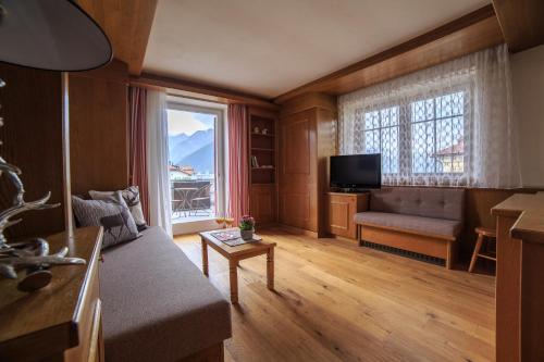 a living room with a couch and a large window at Sapelza Appartementhaus in Dobbiaco
