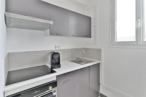 une cuisine blanche avec un évier et une cuisinière dans l'établissement Studio tout équipé à Montreuil proche Paris, à Montreuil