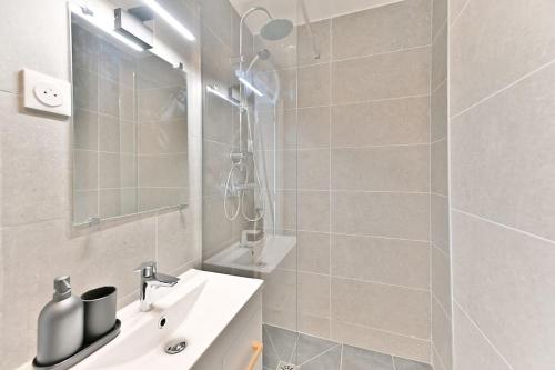 une salle de bain blanche avec une douche et un lavabo dans l'établissement Studio tout équipé à Montreuil proche Paris, à Montreuil