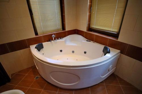 a large white tub in a bathroom with two windows at Хотел Свети Трифон in Melnik