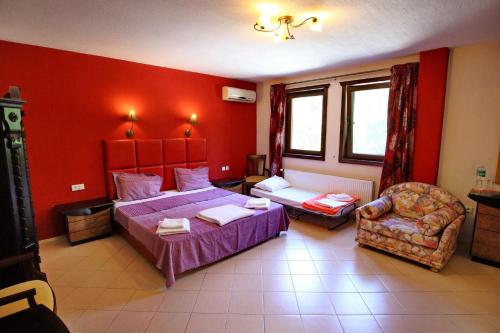 a bedroom with red walls and a bed and a chair at Хотел Свети Трифон in Melnik