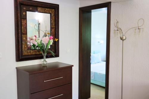 a bedroom with a dresser with a vase of flowers on it at Хотел Свети Трифон in Melnik