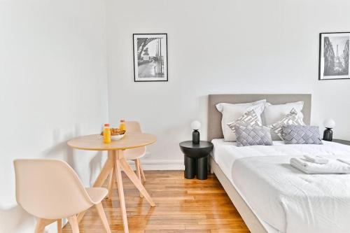 une chambre blanche avec un lit et une table dans l'établissement Studio confortable - Havre de Paix proche Paris, à Montreuil