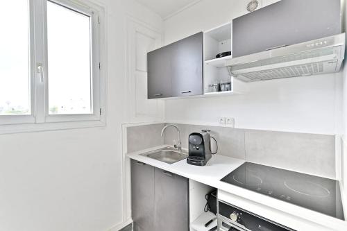 une cuisine blanche avec un évier et une fenêtre dans l'établissement Studio confortable - Havre de Paix proche Paris, à Montreuil