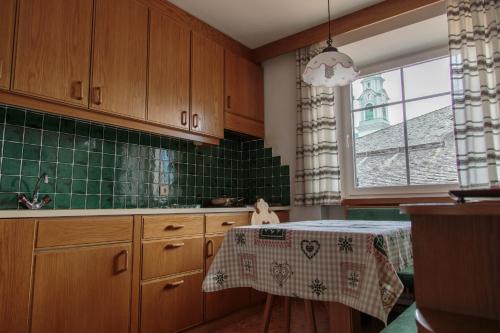 a kitchen with a table and a green tiled wall at Sapelza Appartementhaus in Dobbiaco