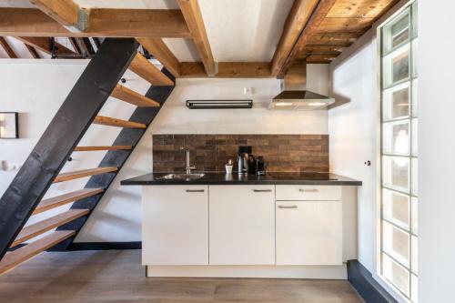 a kitchen with white cabinets and a staircase at Grapèlli Boutique Hotel in Alkmaar