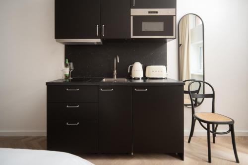 a black kitchen with a sink and a microwave at OLD NOT WORKING Zentrales Studio Apartment Fair HBF-Messe-ÖVB ARENA in Bremen