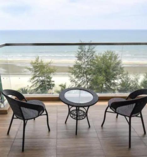 three chairs and a table in front of a large window at Timurbay Seafront Residence & Suites in Kuantan