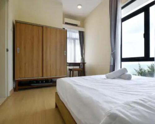 a bedroom with a large white bed and a window at Timurbay Seafront Residence & Suites in Kuantan