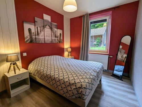 a bedroom with a bed with red walls and a window at Appartement 5 personnes à deux kilomètres des pistes in La Bresse