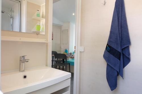 łazienka z umywalką i niebieskim ręcznikiem na ścianie w obiekcie Happy Camp mobile homes in Camping Villaggio Lamaforca w mieście Carovigno