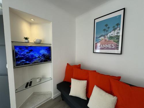 - un salon avec un canapé rouge et un aquarium dans l'établissement Studio confortable proche mer deb1890, à Cannes