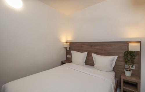 a bedroom with a large bed with white sheets and pillows at Hotel la Perle Montparnasse in Paris