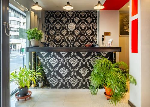 une pièce avec des plantes en pot sur un mur dans l'établissement Hotel la Perle Montparnasse, à Paris