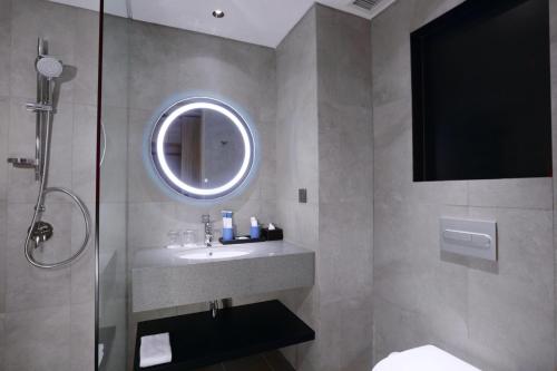 a bathroom with a sink and a shower with a mirror at Grand Aston Puncak Hotel & Resort in Puncak