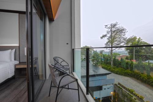 a room with a balcony with a bed and a view at Grand Aston Puncak Hotel & Resort in Puncak