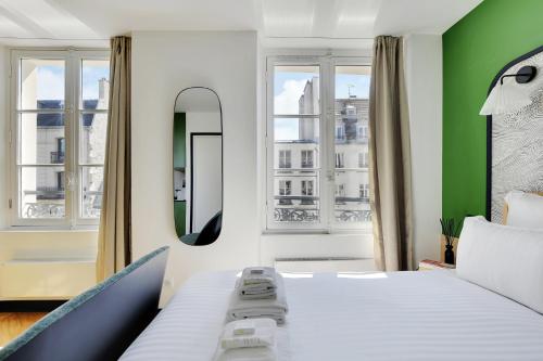 une chambre avec un lit blanc et un mur vert dans l'établissement SERENERS - Charming Serviced Apartments - Bastille, à Paris