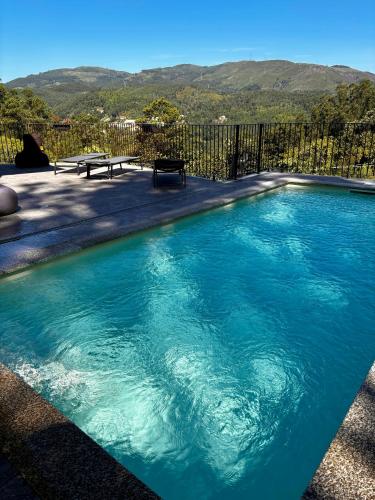 a swimming pool with blue water in front of a fence at QG Quinta de Grovelas in Balança
