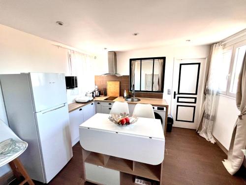 une cuisine avec un réfrigérateur blanc et une table dans l'établissement Appartement à mi chemin entre aéroport et centre ville - Vue sur les montagnes - Echappée Belle, à Perpignan