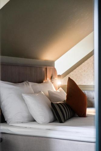 a bed with a bunch of pillows on it at Home Hotel Grand Sundsvall in Sundsvall