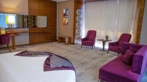 a hotel room with a bed and purple chairs at Gold Majesty Hotel in Bursa