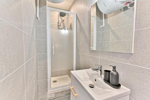 une salle de bain blanche avec un lavabo et un miroir dans l'établissement Studio pour Couple 2 personnes proche de Paris, à Montreuil