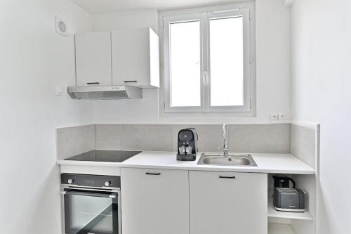 une cuisine avec des armoires blanches et un évier dans l'établissement Studio pour Couple 2 personnes proche de Paris, à Montreuil