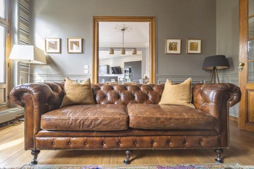 - un canapé en cuir brun dans le salon dans l'établissement L'Élégance Vue Parc, à Reims