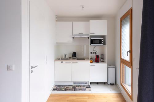 パリにあるLOFT Paris la Villetteの白いキャビネットと窓付きの白いキッチン