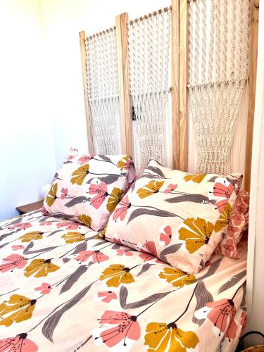 - un lit avec une couette à fleurs et 2 oreillers dans l'établissement Appartement à mi chemin entre aéroport et centre ville - Vue sur les montagnes - Echappée Belle, à Perpignan