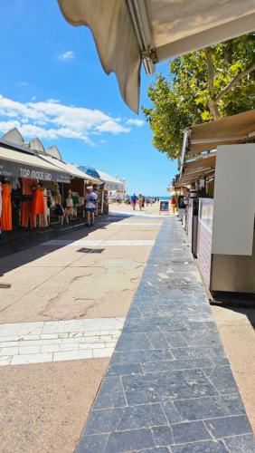 a street with shops on the side of a sidewalk at Studio cabine vue mer linge de maison fournis in La Grande-Motte
