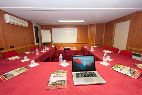 a conference room with red tables with a laptop on them at Brit Hotel Agen - L'Aquitaine in Le Passage