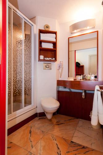 a bathroom with a toilet and a sink and a mirror at Brit Hotel Agen - L'Aquitaine in Le Passage