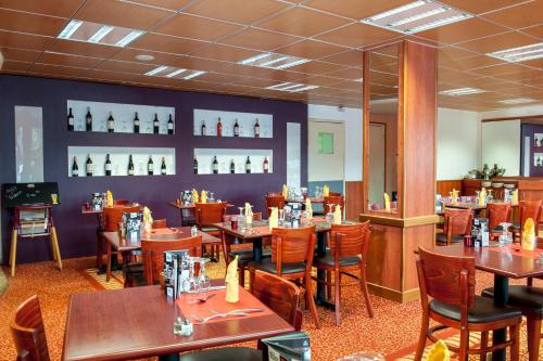 a dining room with wooden tables and chairs at Brit Hotel Agen - L'Aquitaine in Le Passage