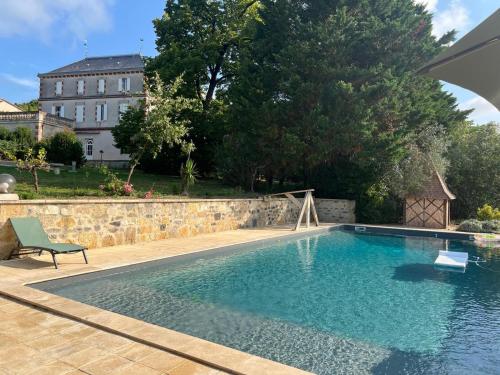 a swimming pool in a yard with a stone wall at Maison d'hôtes à Laplume in Laplume