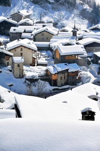un village enneigé avec des maisons et une église dans l'établissement Chez Michel, à Sainte-Foy-Tarentaise