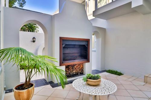 a patio with a fireplace and a potted plant at Hermanus Beachfront Lodge - Solar Power in Hermanus