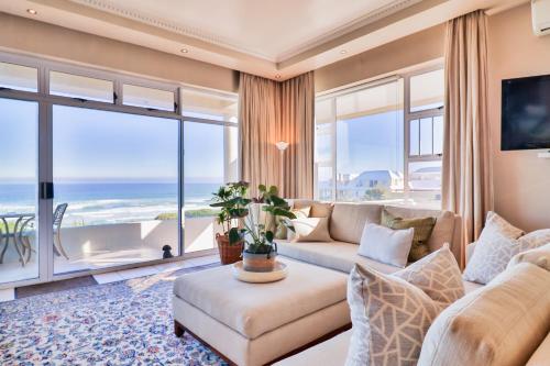 a living room with a couch and a view of the ocean at Hermanus Beachfront Lodge - Solar Power in Hermanus
