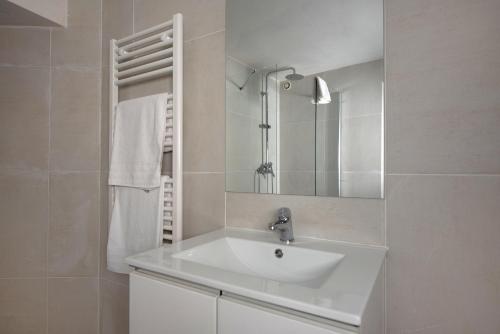 une salle de bain blanche avec un lavabo et un miroir dans l'établissement Le Cocon, à Avignon