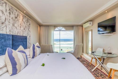 a bedroom with a large bed with a view of the ocean at Hermanus Beachfront Lodge - Solar Power in Hermanus