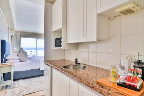 a kitchen with a sink and a bedroom with a bed at Hermanus Beachfront Lodge - Solar Power in Hermanus