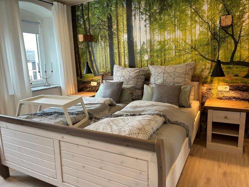 a bedroom with a bed and a wall with trees at Ferienhaus Klaus in Kirchenlamitz